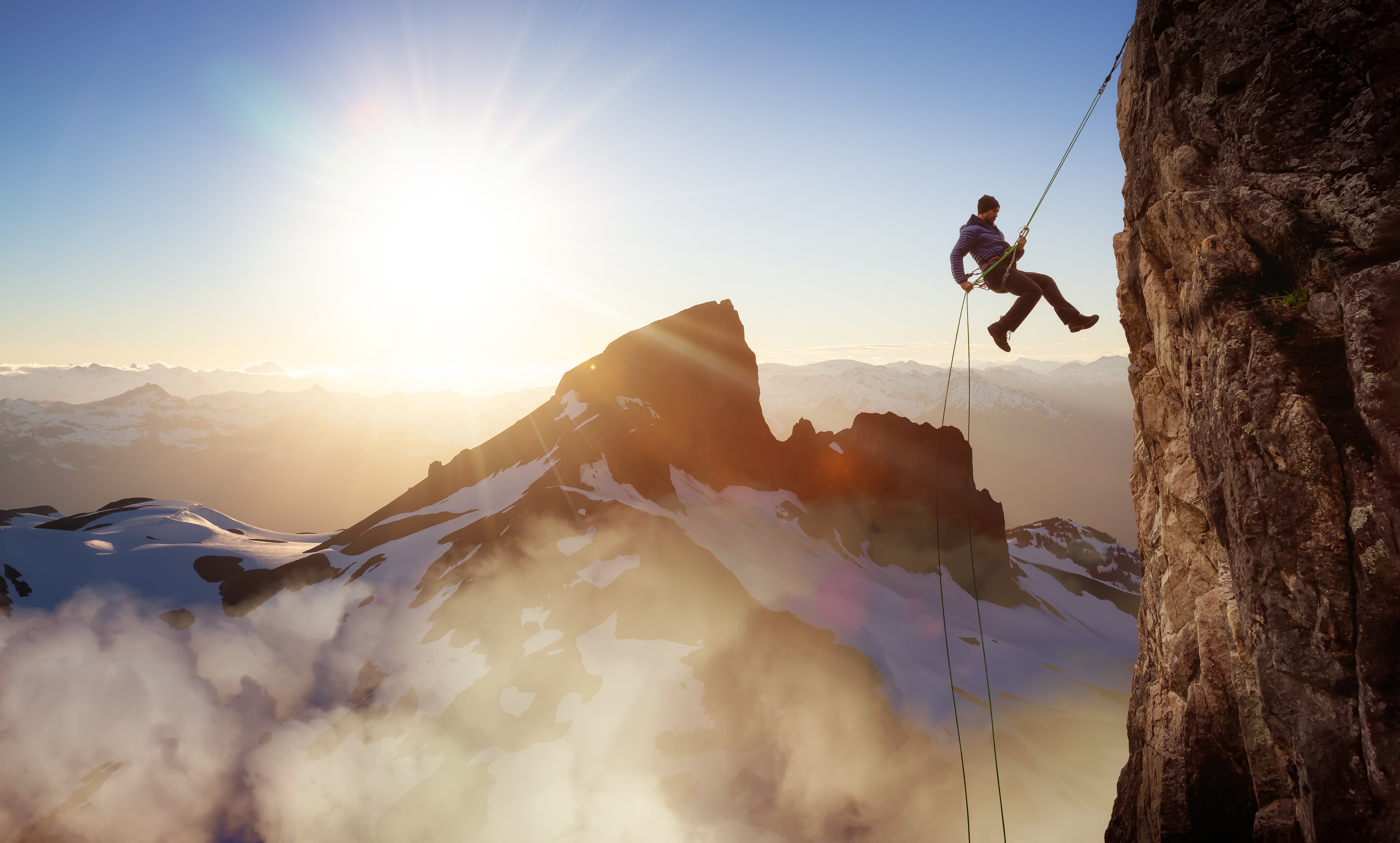 Professional climber scaling rock face at sunset